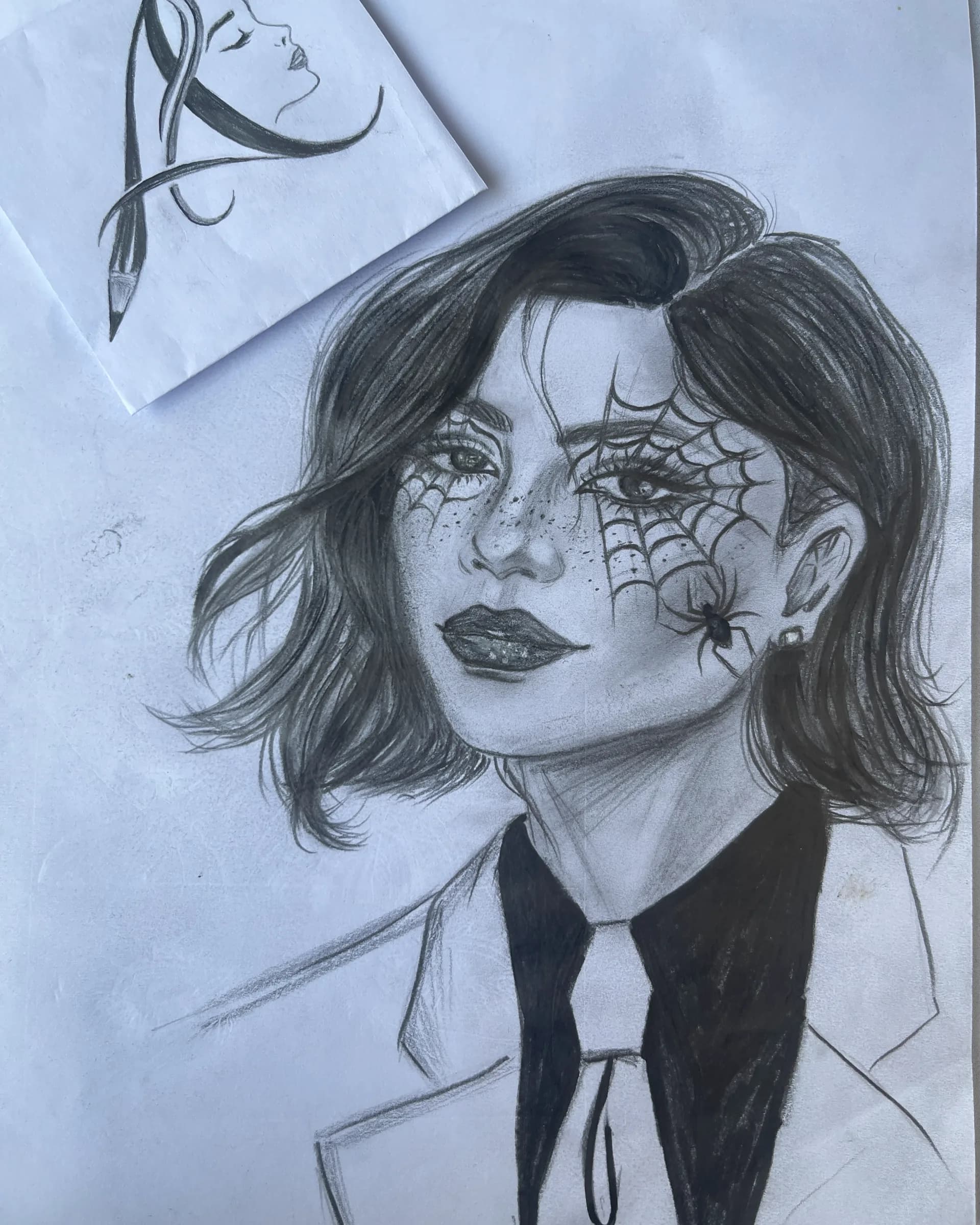 Hand-drawn graphite gothic character portrait featuring a woman with spiderweb eye details, a small spider, freckles, dark hair, and dramatic shading by Ammama Sketch.