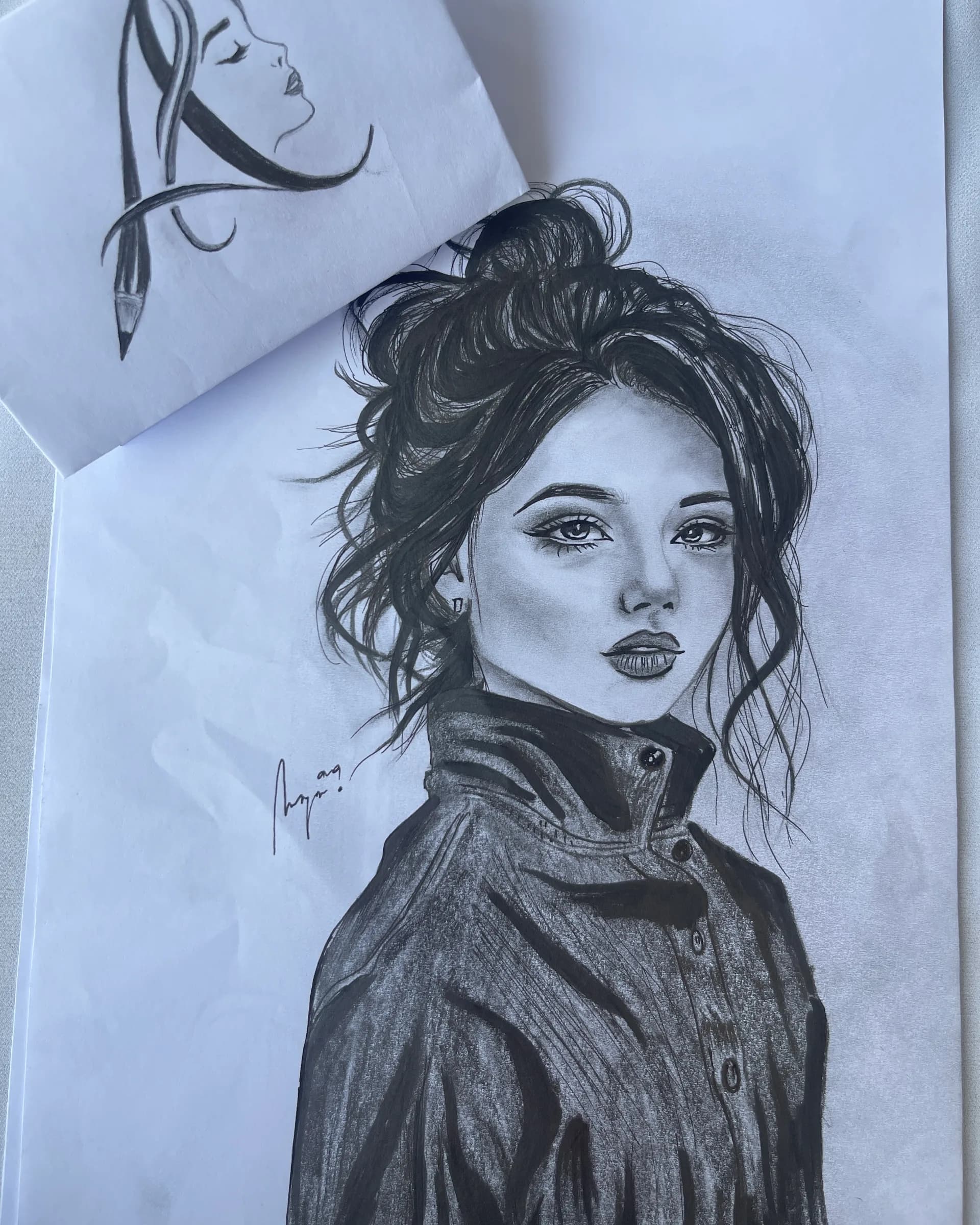 Hand-drawn graphite portrait of a stylish young woman with an updo hairstyle, expressive eyes, and detailed fashion clothing by Ammama Sketch.