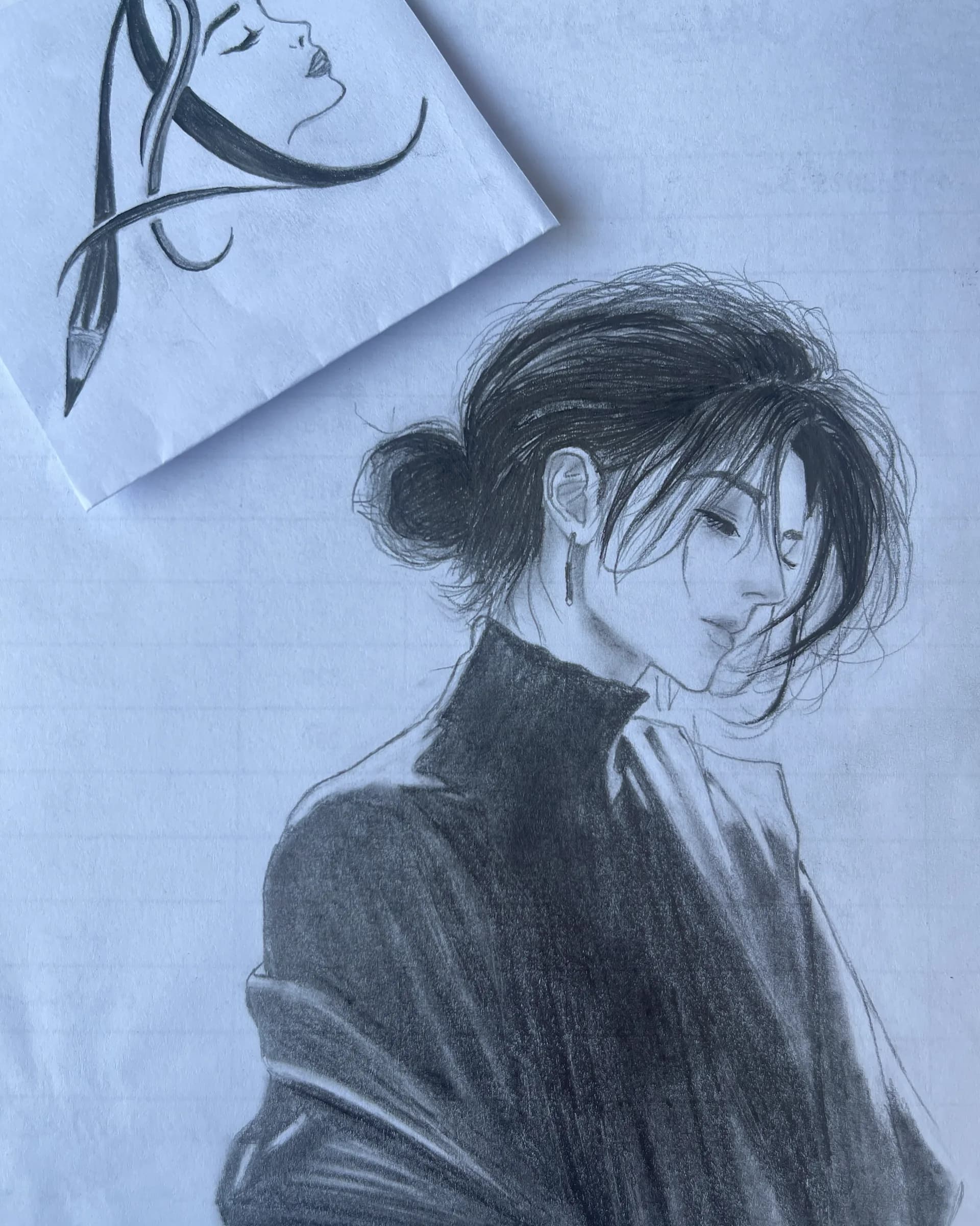 Hand-drawn graphite portrait of a young woman with her hair tied in a bun, head gently lowered, dark clothing, and soft expressive shading by Ammama Sketch.