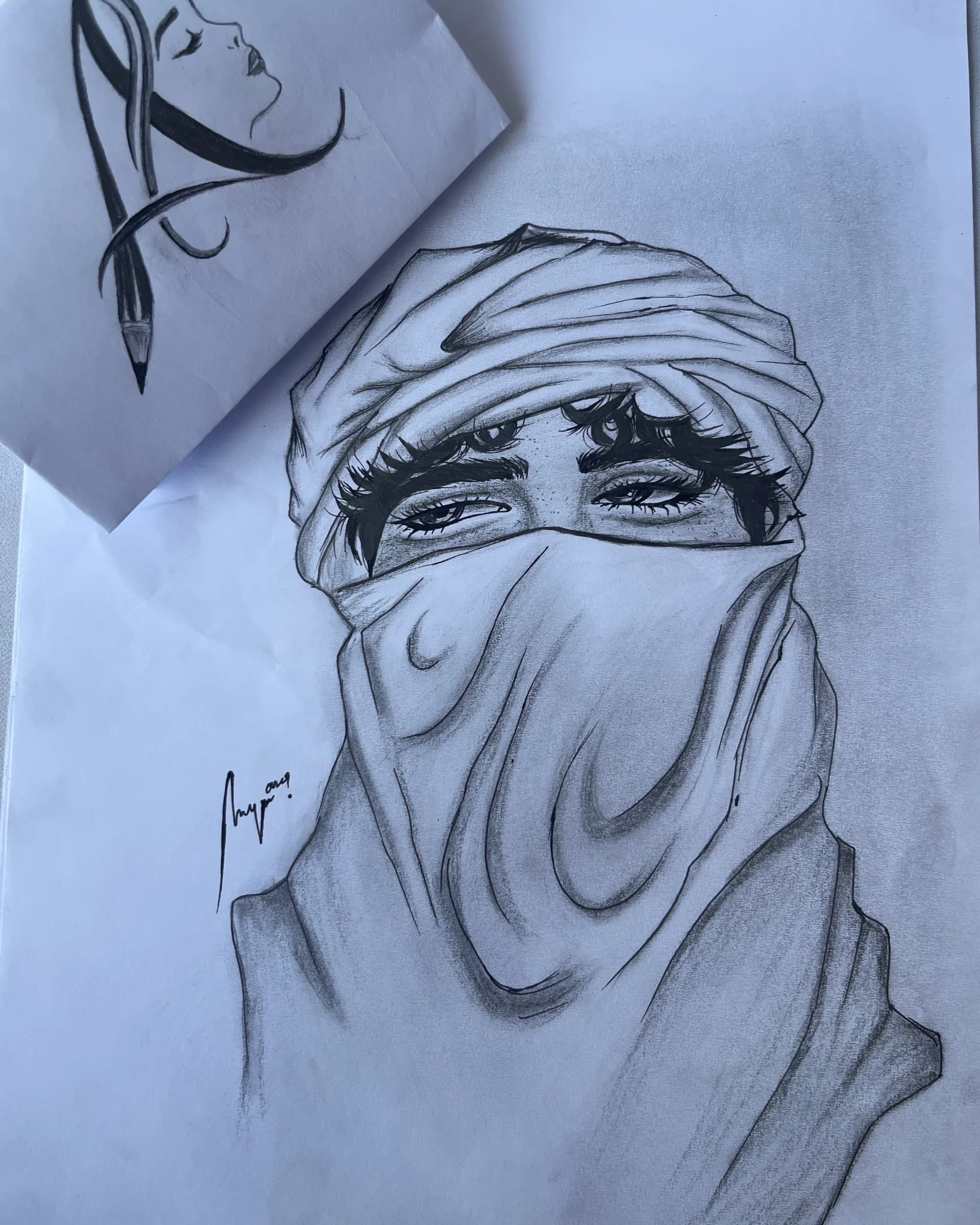 Hand-drawn graphite portrait of a veiled woman with expressive eyes, detailed lashes, layered fabric folds, and soft pencil shading by Ammama Sketch.