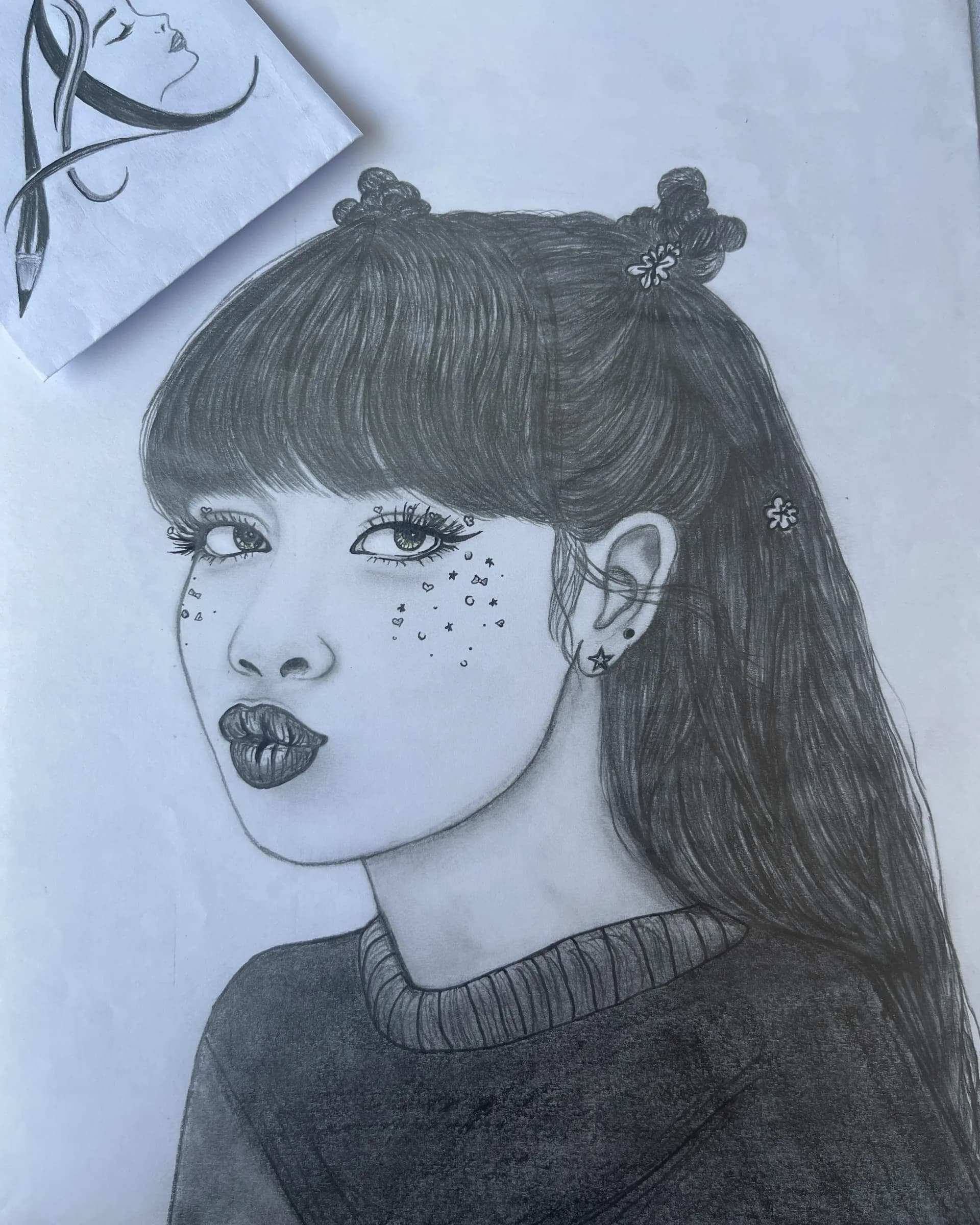 Hand-drawn graphite character portrait of a young woman with twin buns, long dark hair, decorative freckles, star details, and expressive eyes by Ammama Sketch.
